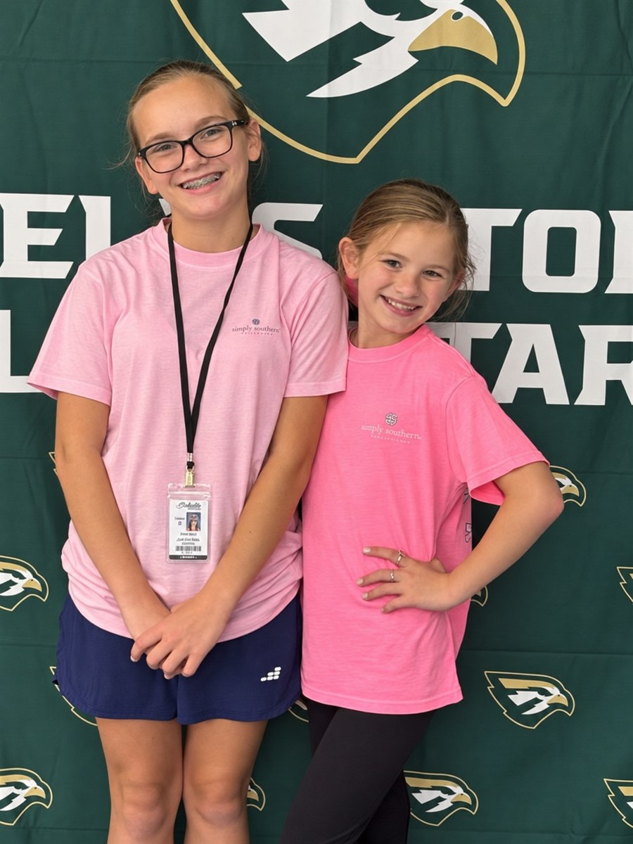 Two smiling sisters wearing pink shirts