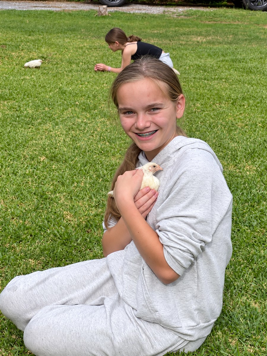 A girl smiling while gently holding a chick